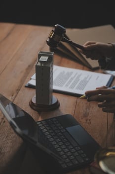 Real Estate Law, Home Insurance, property Tax, Auction and Bidding concepts. small toy house model with gavel justice hammer on desk in courthouse. photo