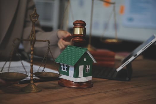 Real Estate Law, Home Insurance, property Tax, Auction and Bidding concepts. small toy house model with gavel justice hammer on desk in courthouse. photo