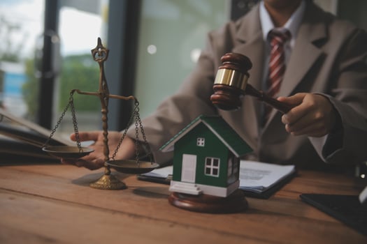 Real Estate Law, Home Insurance, property Tax, Auction and Bidding concepts. small toy house model with gavel justice hammer on desk in courthouse. photo