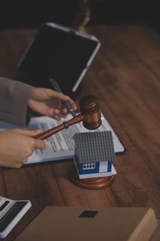 Real Estate Law, Home Insurance, property Tax, Auction and Bidding concepts. small toy house model with gavel justice hammer on desk in courthouse. photo