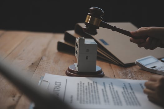 Real Estate Law, Home Insurance, property Tax, Auction and Bidding concepts. small toy house model with gavel justice hammer on desk in courthouse. photo