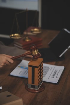 Real Estate Law, Home Insurance, property Tax, Auction and Bidding concepts. small toy house model with gavel justice hammer on desk in courthouse. photo