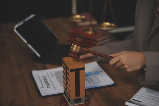 Real Estate Law, Home Insurance, property Tax, Auction and Bidding concepts. small toy house model with gavel justice hammer on desk in courthouse. photo