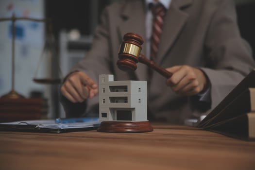 Real Estate Law, Home Insurance, property Tax, Auction and Bidding concepts. small toy house model with gavel justice hammer on desk in courthouse. photo