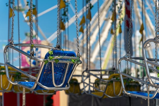 row of swings with green and blue seats hanging from a chain photo