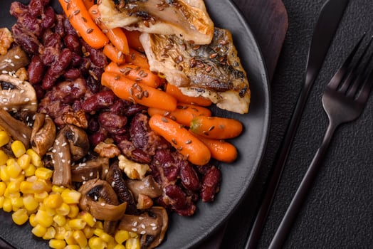 A colorful vegetarian dish consists of fish, beans, corn, mushrooms photo