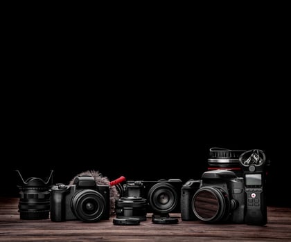 Different modern cameras and lenses on a wooden table. Technique for shooting photos and videos. blogger kit. Postcard concept for photographer and videographer.