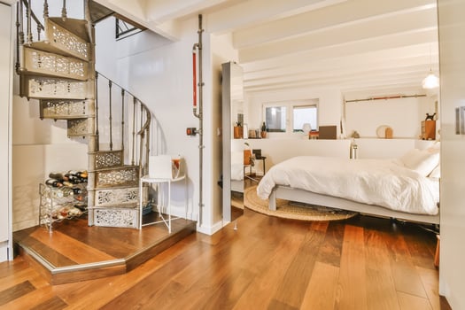 A bedroom with a spiral staircase leading to a bed photo