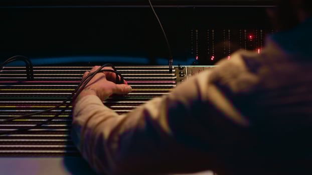 Music producer fixing coiled cable inside amplifier or audio compressor, prepares control room technical equipment for a recording session. Sound engineer works on producing tracks. Camera A. photo