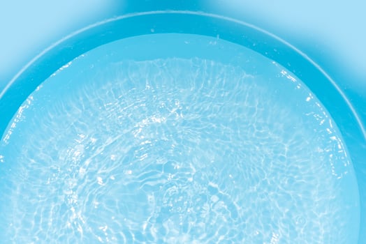 Bluewater waves on the surface ripples blurred. Defocus blurred transparent blue colored clear calm water surface texture with splash and bubbles. Water waves with shining pattern texture background. photo