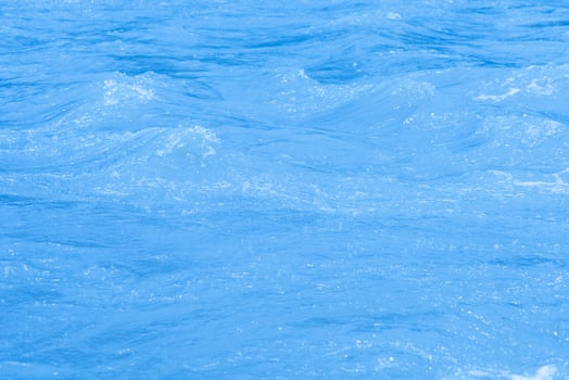 Bluewater waves on the surface ripples blurred. Defocus blurred transparent blue colored clear calm water surface texture with splash and bubbles. Water waves with shining pattern texture background. photo