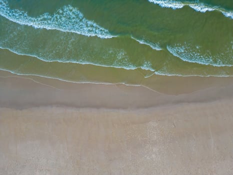 Relaxing aerial beach scene, summer vacation holiday template banner. Waves surf with amazing blue ocean lagoon, sea shore, coastline. Perfect aerial drone top view. Peaceful bright beach, seaside photo