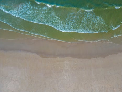 Relaxing aerial beach scene, summer vacation holiday template banner. Waves surf with amazing blue ocean lagoon, sea shore, coastline. Perfect aerial drone top view. Peaceful bright beach, seaside photo