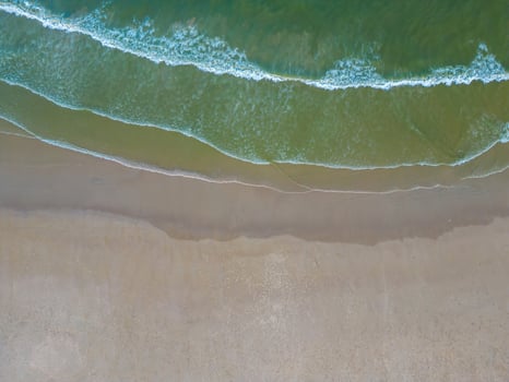 Relaxing aerial beach scene, summer vacation holiday template banner. Waves surf with amazing blue ocean lagoon, sea shore, coastline. Perfect aerial drone top view. Peaceful bright beach, seaside photo
