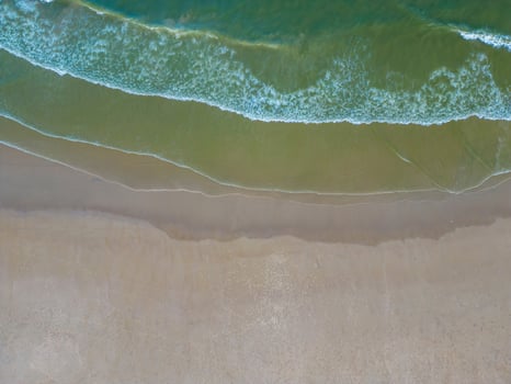 Relaxing aerial beach scene, summer vacation holiday template banner. Waves surf with amazing blue ocean lagoon, sea shore, coastline. Perfect aerial drone top view. Peaceful bright beach, seaside photo