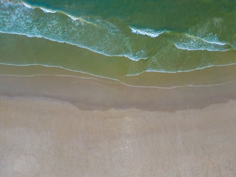 Relaxing aerial beach scene, summer vacation holiday template banner. Waves surf with amazing blue ocean lagoon, sea shore, coastline. Perfect aerial drone top view. Peaceful bright beach, seaside photo