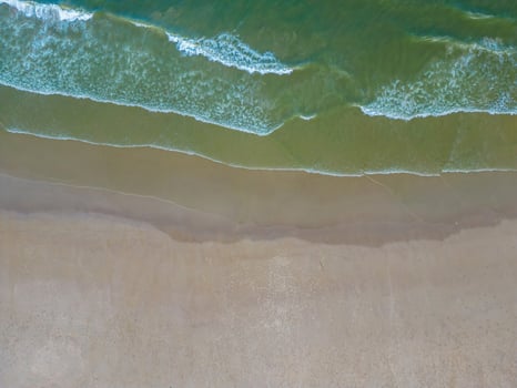 Relaxing aerial beach scene, summer vacation holiday template banner. Waves surf with amazing blue ocean lagoon, sea shore, coastline. Perfect aerial drone top view. Peaceful bright beach, seaside photo