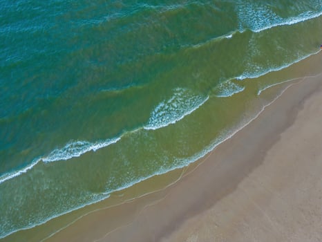 Relaxing aerial beach scene, summer vacation holiday template banner. Waves surf with amazing blue ocean lagoon, sea shore, coastline. Perfect aerial drone top view. Peaceful bright beach, seaside photo