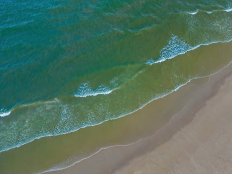 Relaxing aerial beach scene, summer vacation holiday template banner. Waves surf with amazing blue ocean lagoon, sea shore, coastline. Perfect aerial drone top view. Peaceful bright beach, seaside photo