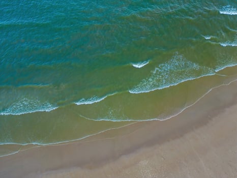 Relaxing aerial beach scene, summer vacation holiday template banner. Waves surf with amazing blue ocean lagoon, sea shore, coastline. Perfect aerial drone top view. Peaceful bright beach, seaside photo