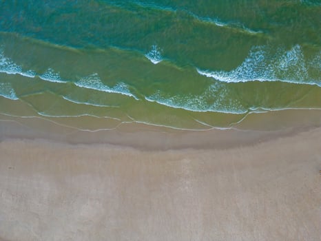 Relaxing aerial beach scene, summer vacation holiday template banner. Waves surf with amazing blue ocean lagoon, sea shore, coastline. Perfect aerial drone top view. Peaceful bright beach, seaside photo