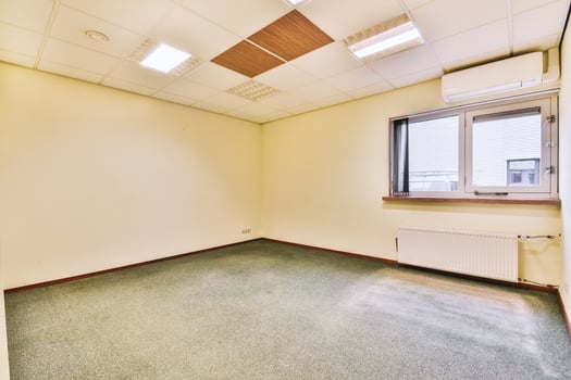 An empty office with a window and carpet photo