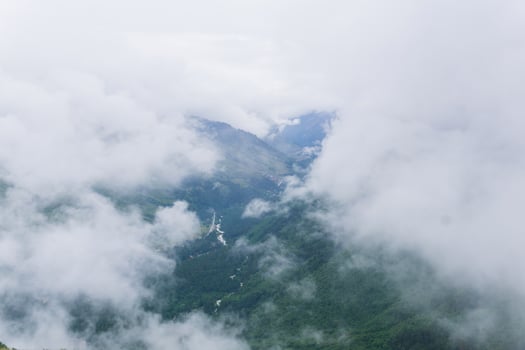 aerial view of wild forested mountain slope through clouds photo
