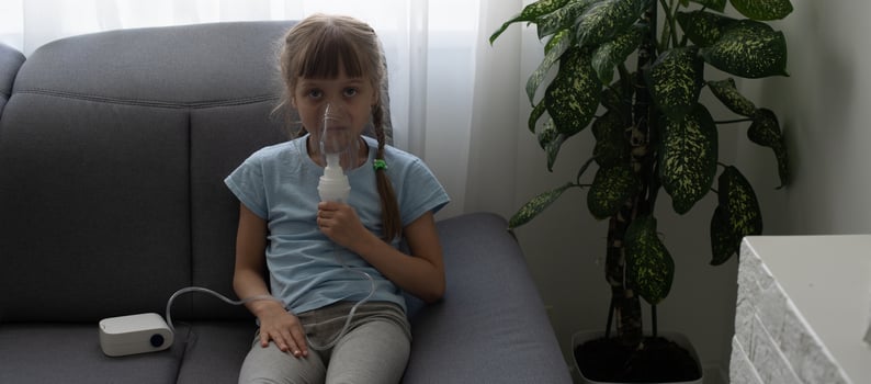 Little girl making inhalation with nebulizer at home. child asthma inhaler inhalation nebulizer steam sick cough concept. photo