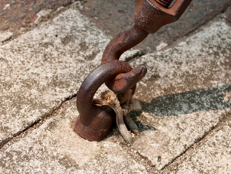 Industrial heavy duty old and rusty hook connector object isolated on horizontal ratio outdoor ground gray brick flooring environment background. photo