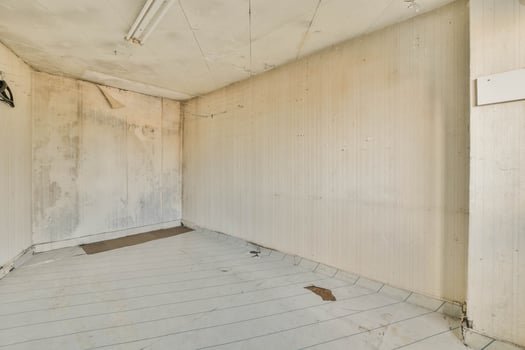An empty room with a white floor and peeling paint photo