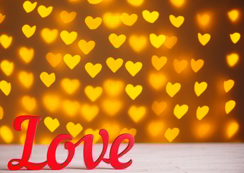 the inscription Love on a wooden background with beautiful hearts made of lights on a blurred background photo