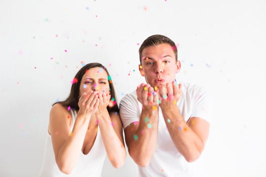 Young man and woman blowing confetti decorations photo