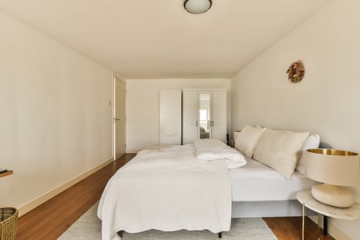 A bedroom with a white bed and wooden floor photo