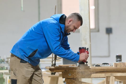 Close Up of Worker Carefully Cutting and Planing Wooden Pieces for Furniture in Wood Industry photo
