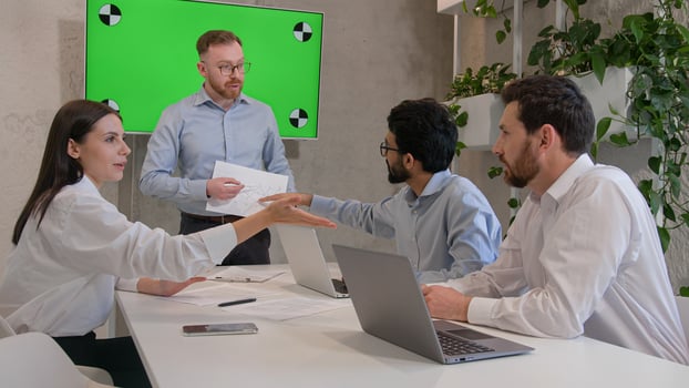 Male leader speaker coach talking to team multiracial men listen to CEO businessman teaching employees showing business presentation at group conference pointing at green interactive board chroma key photo