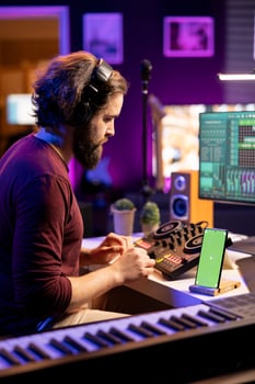 Audio engineer adding sound effects on tunes in post production, working with daw software next to greenscreen layout on mobile phone. Music producer creating sounds on mixing console. photo