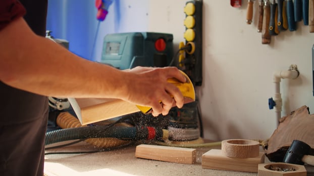 Manufacturer working in joinery using sanding block to remove imperfections on wood piece. Woodworking specialist using coarse grade sandpaper to do manual sanding on lumber, camera B close up photo