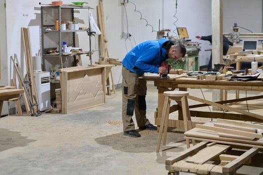 Close Up of Worker Carefully Cutting and Planing Wooden Pieces for Furniture in Wood Industry photo