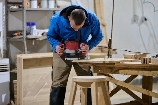 Close Up of Worker Carefully Cutting and Planing Wooden Pieces for Furniture in Wood Industry photo