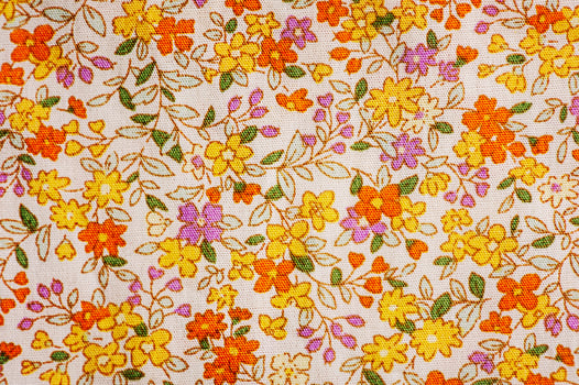 The fabric is beige with a flower of orange, yellow and purple as a background photo