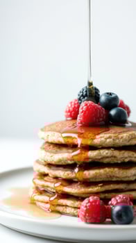 Stack of pancakes with maple syrup and berries photo