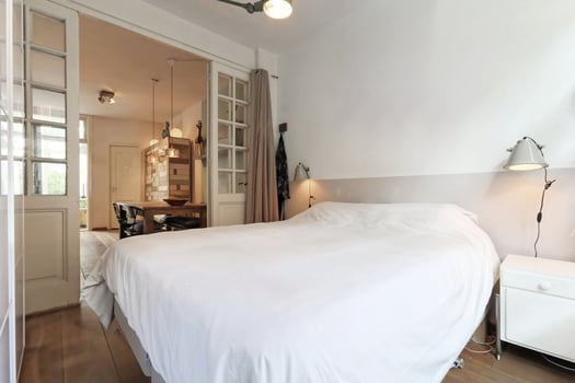 A bedroom with a bed, a table and a window photo