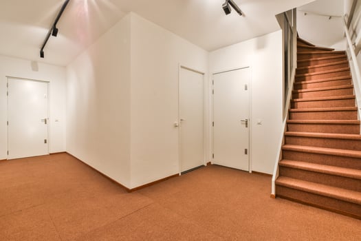 An empty hallway with stairs and a door photo