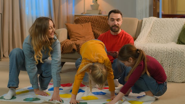Happy family playing funny game twister at home Caucasian parents children play together joyful carefree mother father little girls daughters kids laugh have fun entertainment home weekend childhood photo