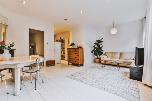 A white room with a table, chairs and a couch photo