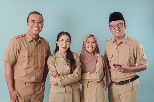 Four Indonesian government workers in khaki uniform posing and smiling to the camera. photo