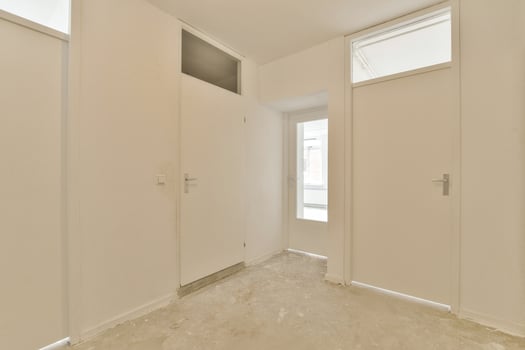 A white hallway with two doors and a window photo