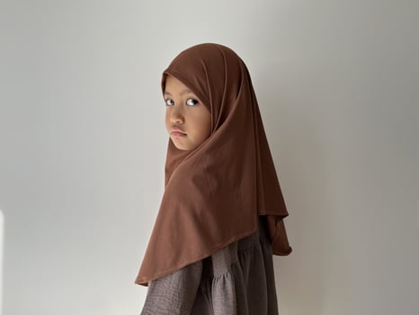 Asian Muslim little girl wearing hijab show sad expression facing sideways photo