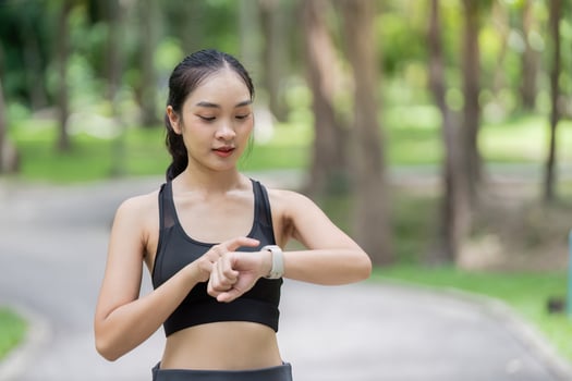 Focused Asian woman checking smartwatch for fitness progress photo
