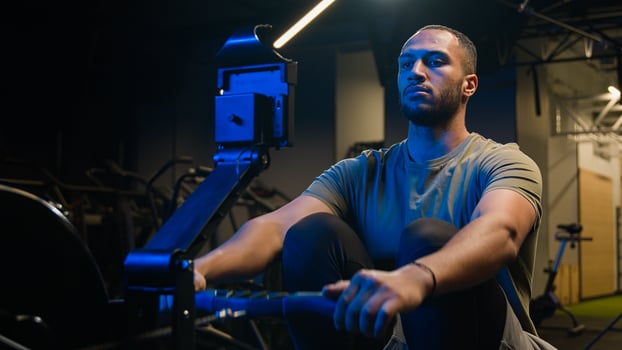 Sport determination hard exercise with equipment in sportive club muscles workout African American strong man sporty male guy athlete sportsman bodybuilder in gym pulling rope rowing machine sitting photo